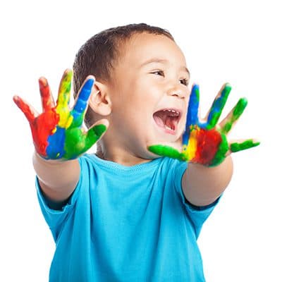 A laughing child showing hands covered in colorful paint