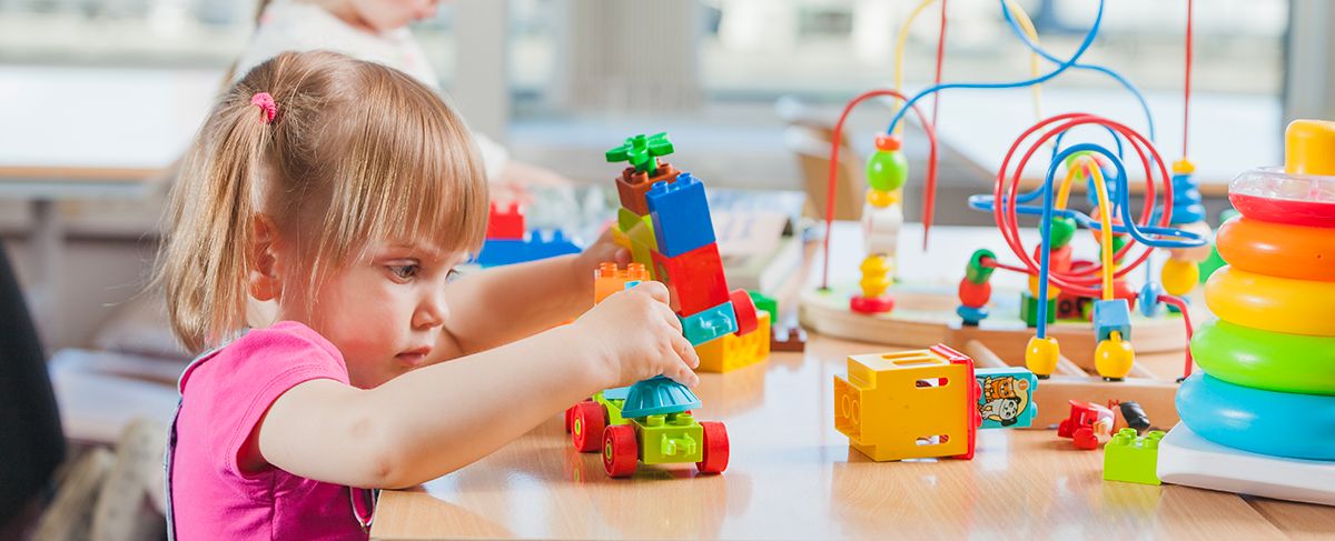 Young child playing with educational toys in classroom.