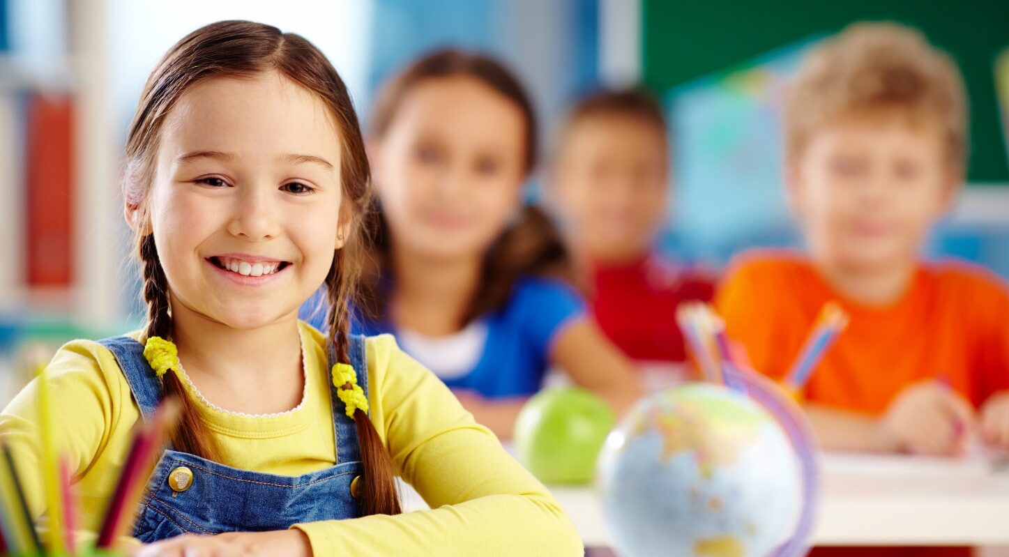Preschool children smiling in a classroom.